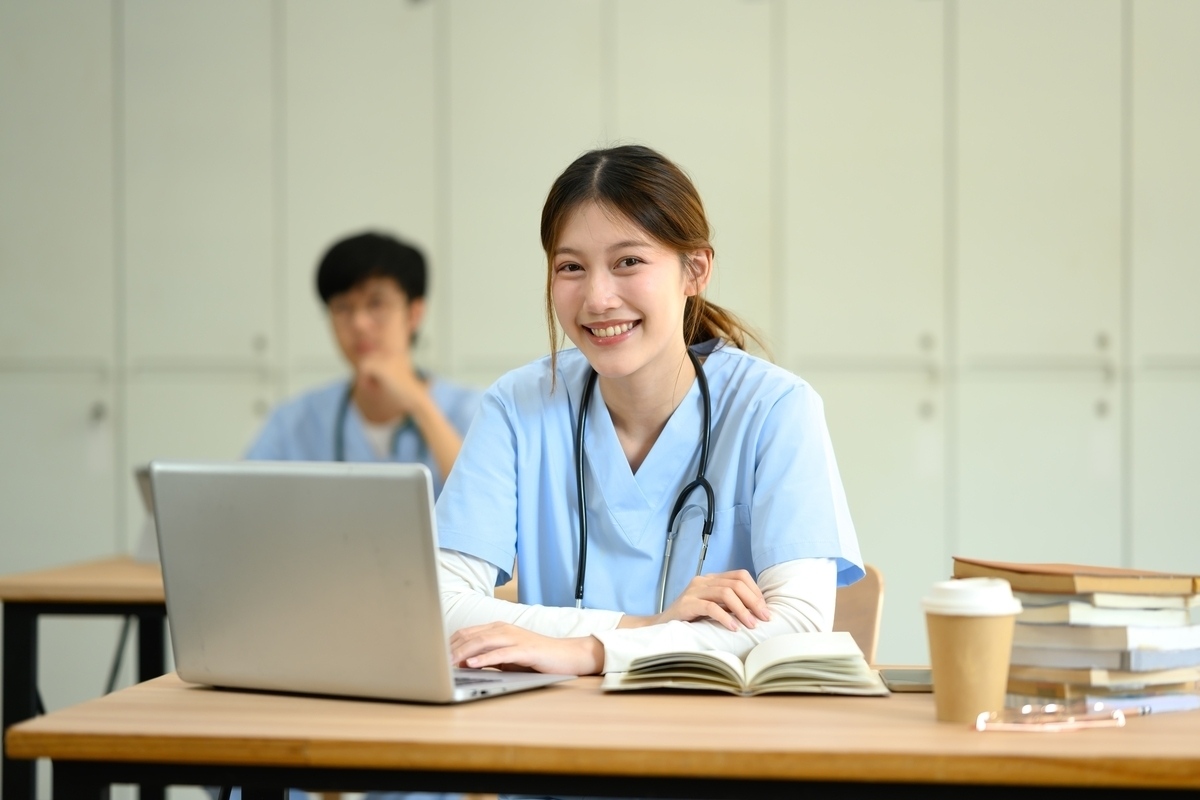 Medical assistant student in scrubs studying on a laptop during medical assistant training in NYC