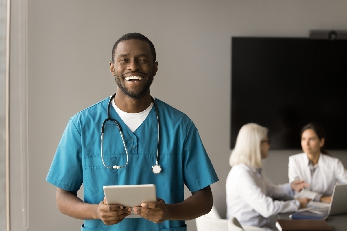 A licensed nurse in scrubs with a stethoscope holding a tablet — representing the CNA to LPN in NYC career advancement pathway