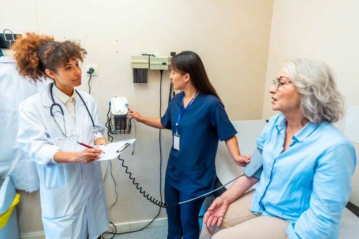 Medical assistant in scrubs taking a patient's blood pressure in an exam room as part of the medical assistant role in NYC