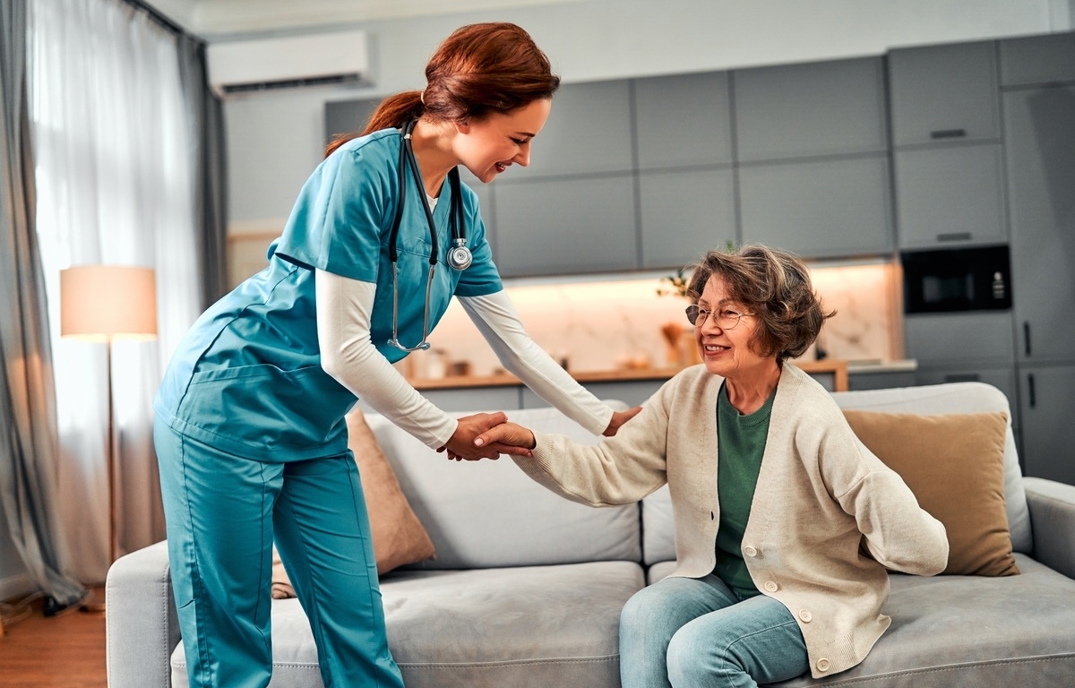 CNA caregiver in scrubs assisting elderly patient with mobility during CNA classes in Queens NY at IP Training School
