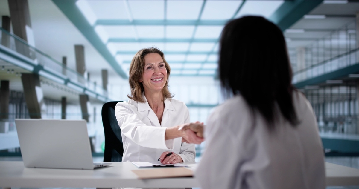 A healthcare professional shaking hands with a candidate representing CNA hiring in Brooklyn at a modern clinical facility