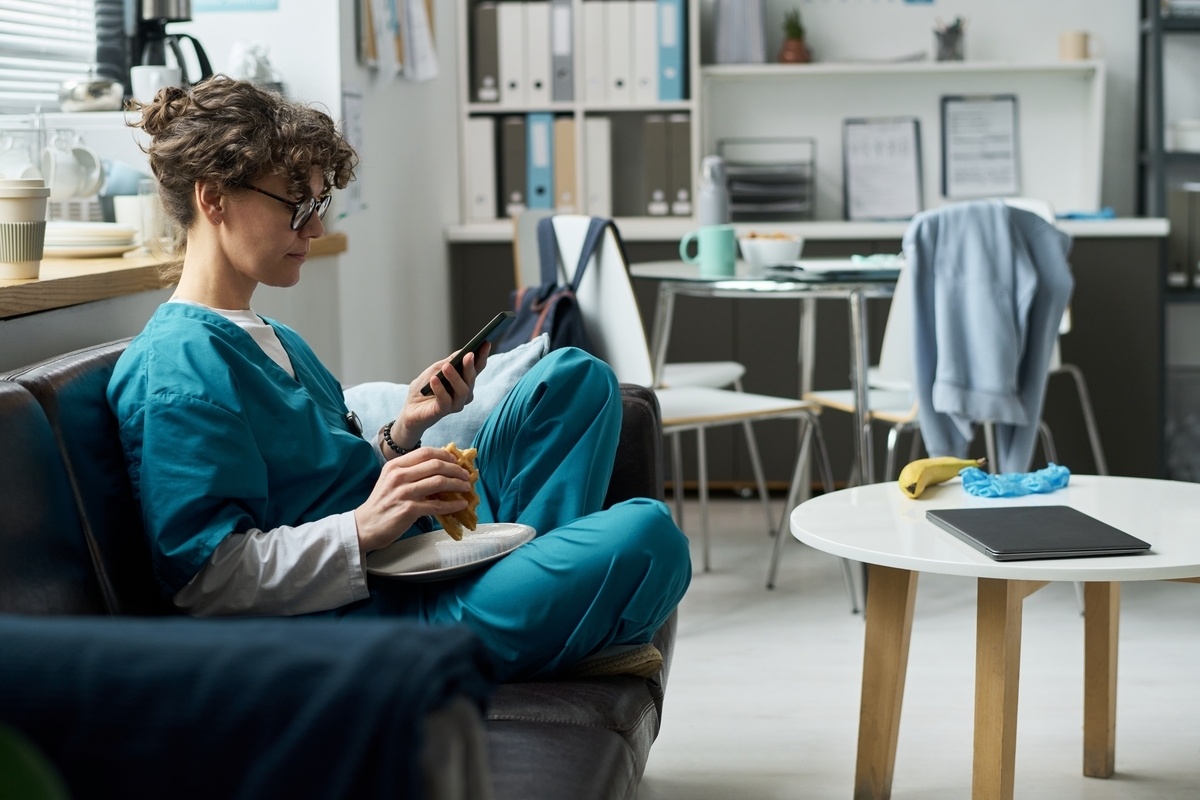A part-time CNA in Brooklyn checks their phone during a break in a healthcare staff room representing flexible scheduling options