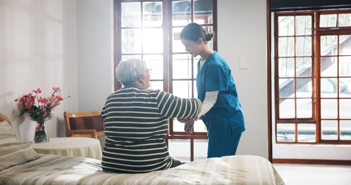 CNA in scrubs providing bedside care to elderly patient representing CNA classes in the Bronx, NY at IP Training School