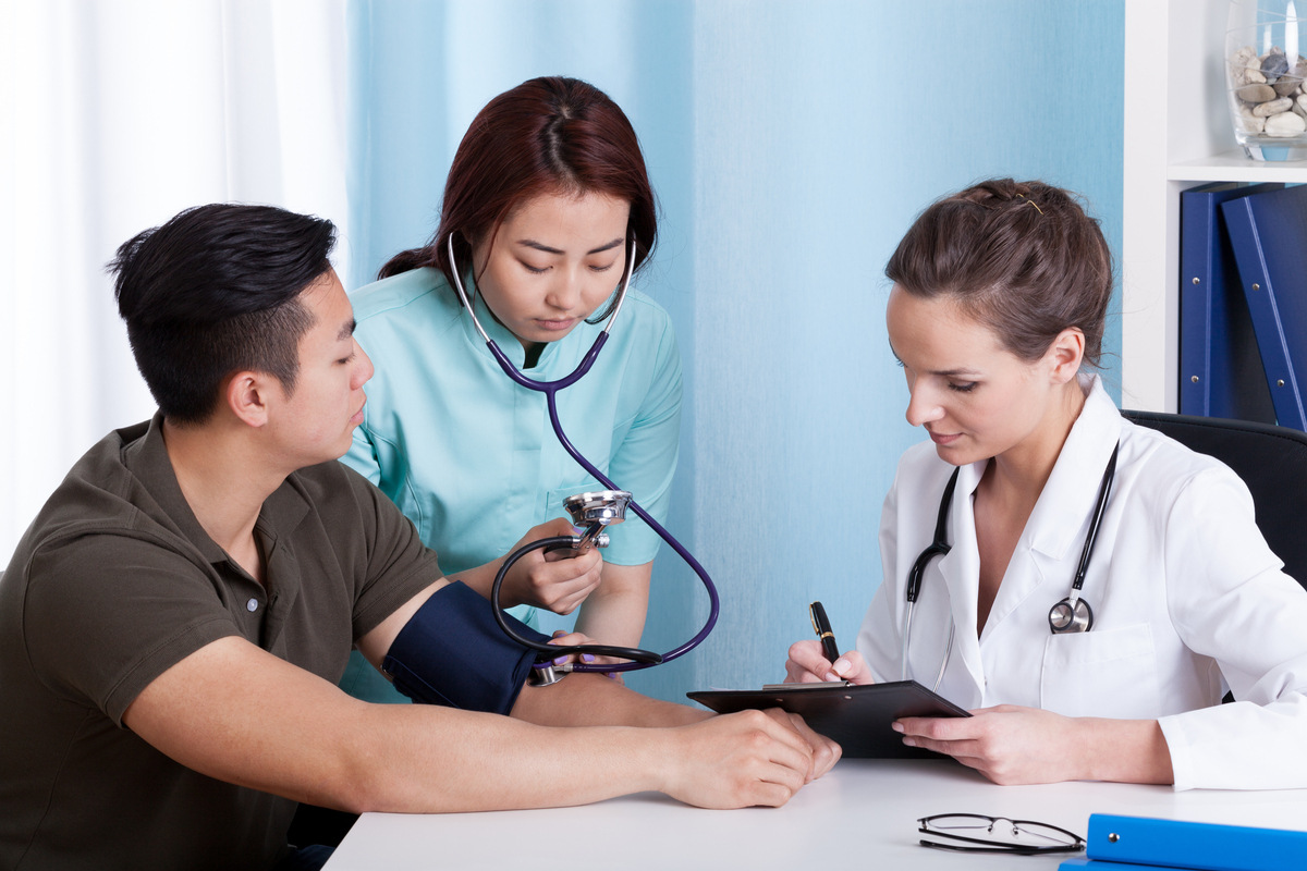 Medical assistant classes in the Bronx student taking a patient's blood pressure in an exam room